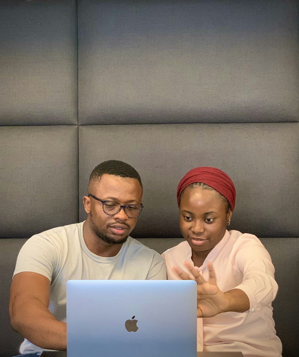 a man and a woman sitting in front of a laptop computer