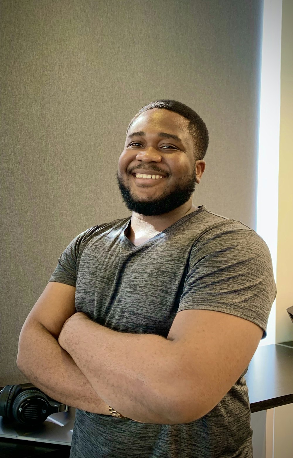 a man with his arms crossed standing in front of a desk