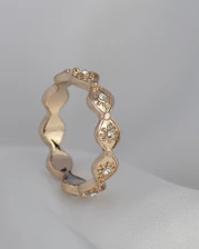 a gold ring with diamonds on a white surface
