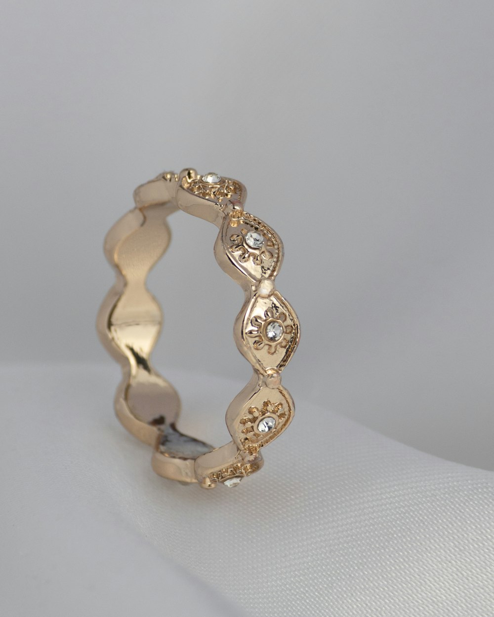 a gold ring with diamonds on a white surface