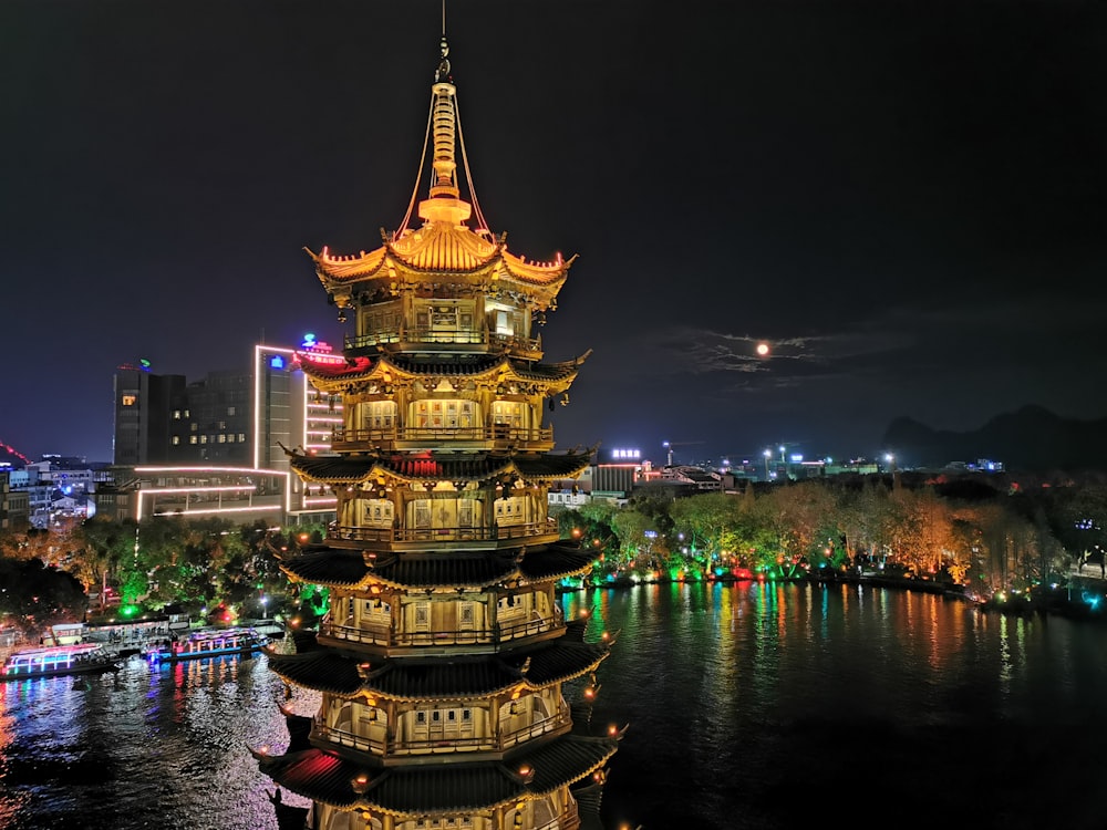 a tall tower sitting on top of a river next to a city