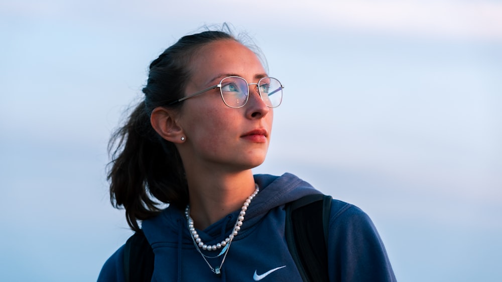 a woman wearing glasses and a pearl necklace