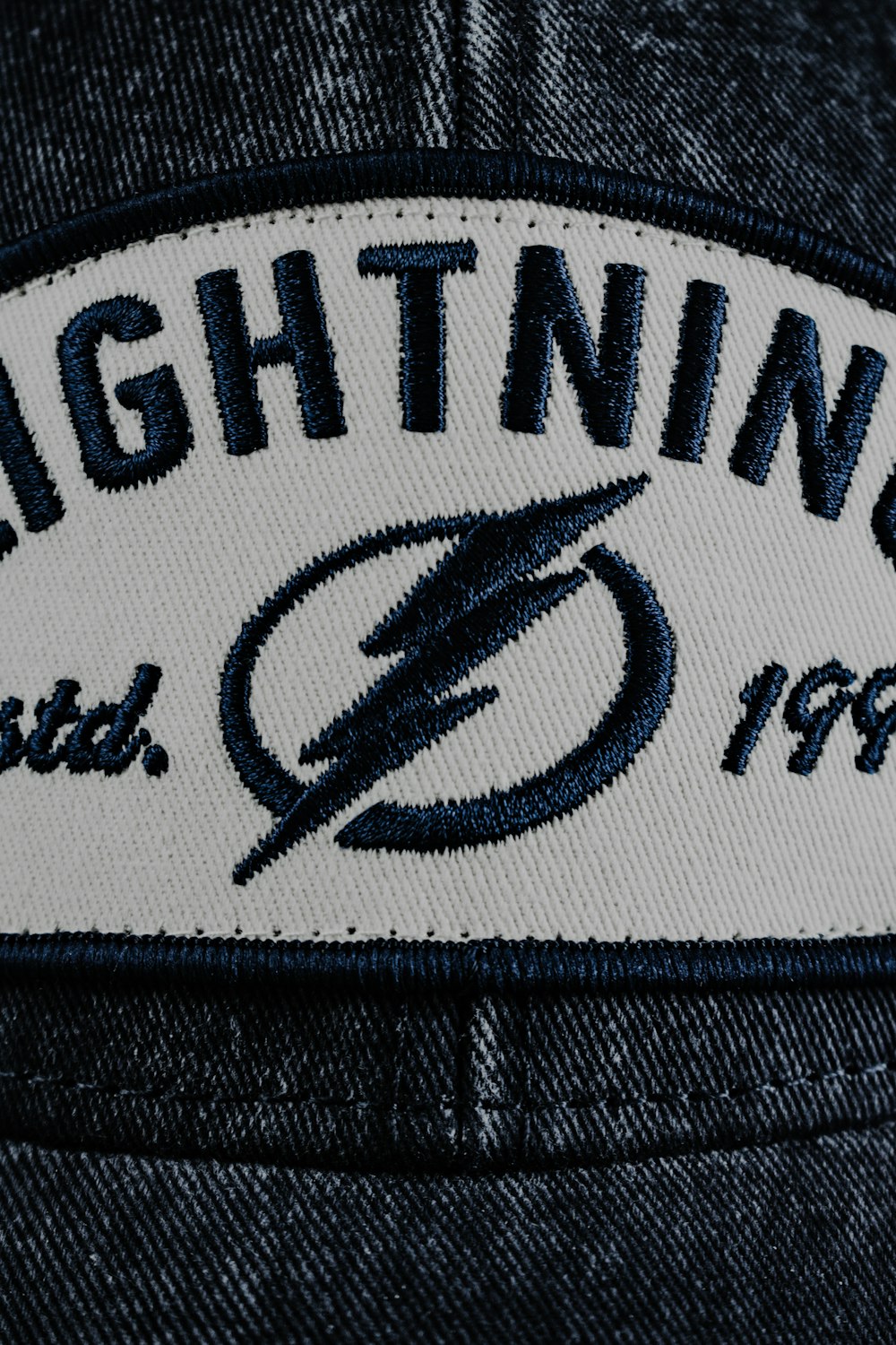 a blue and white hat with a lightning patch on it