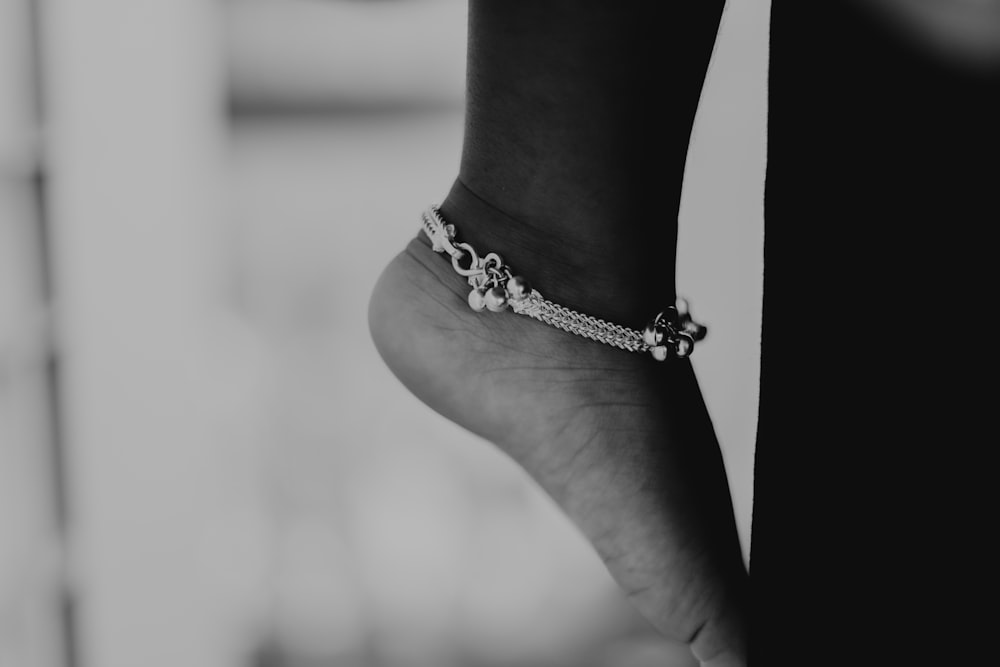 une photo en noir et blanc du pied d’une personne portant un bracelet