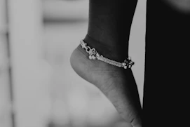 a black and white photo of a person's foot wearing a bracelet