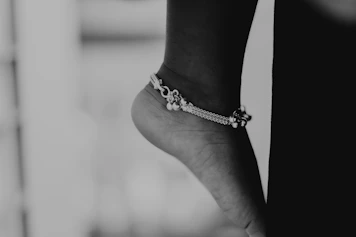 a black and white photo of a person's foot wearing a bracelet