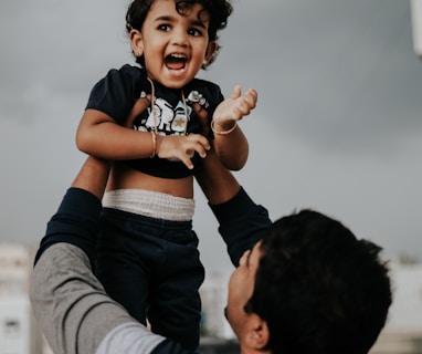 a man holding a small child up in the air