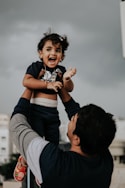 a man holding a small child up in the air