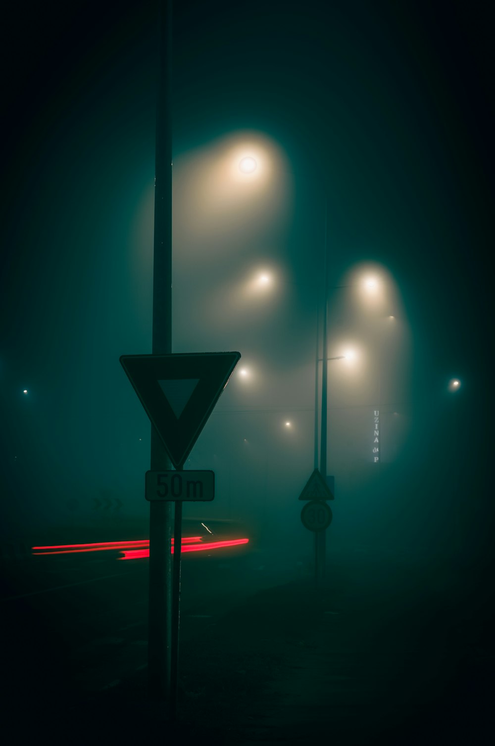 a street sign on a foggy street at night