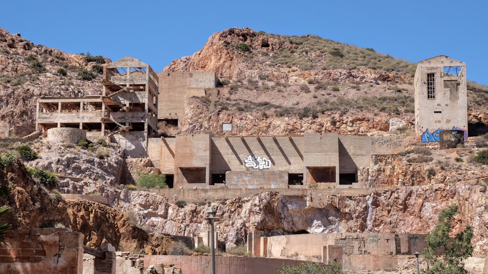 an abandoned building with graffiti on the side of a mountain