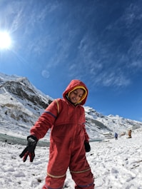a young child in a red snowsuit standing in the snow