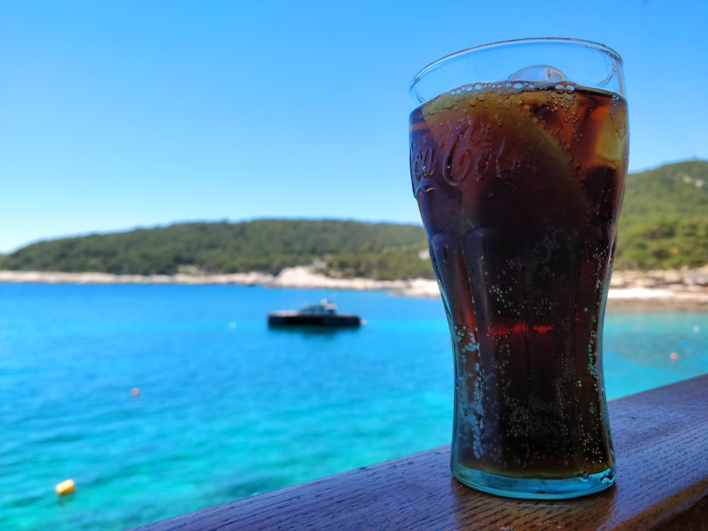 a glass of soda sitting on top of a wooden table