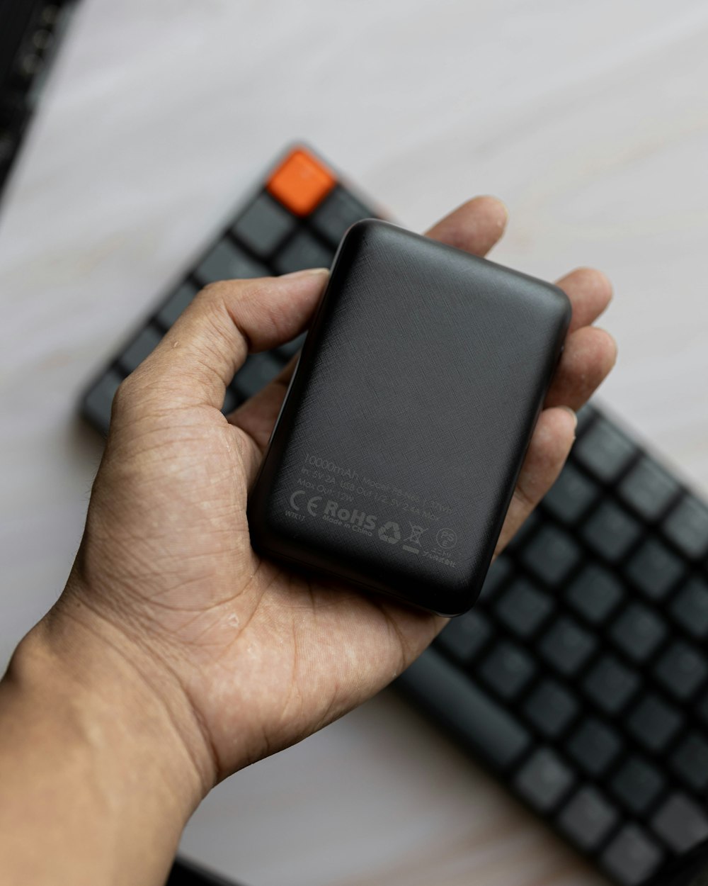 a person holding a cell phone near a keyboard