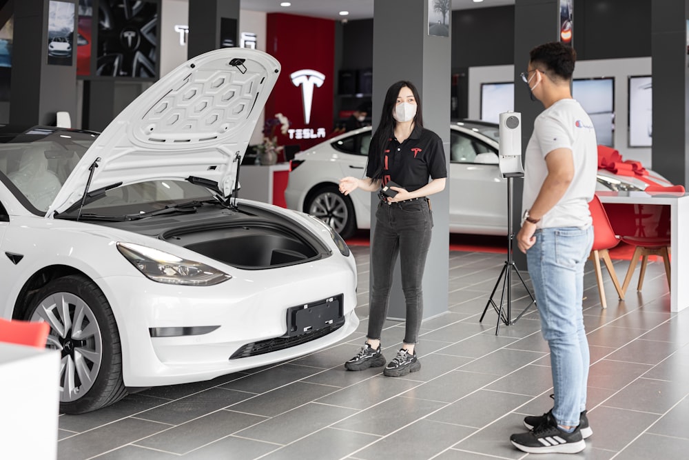 a man and a woman looking at a car in a showroom