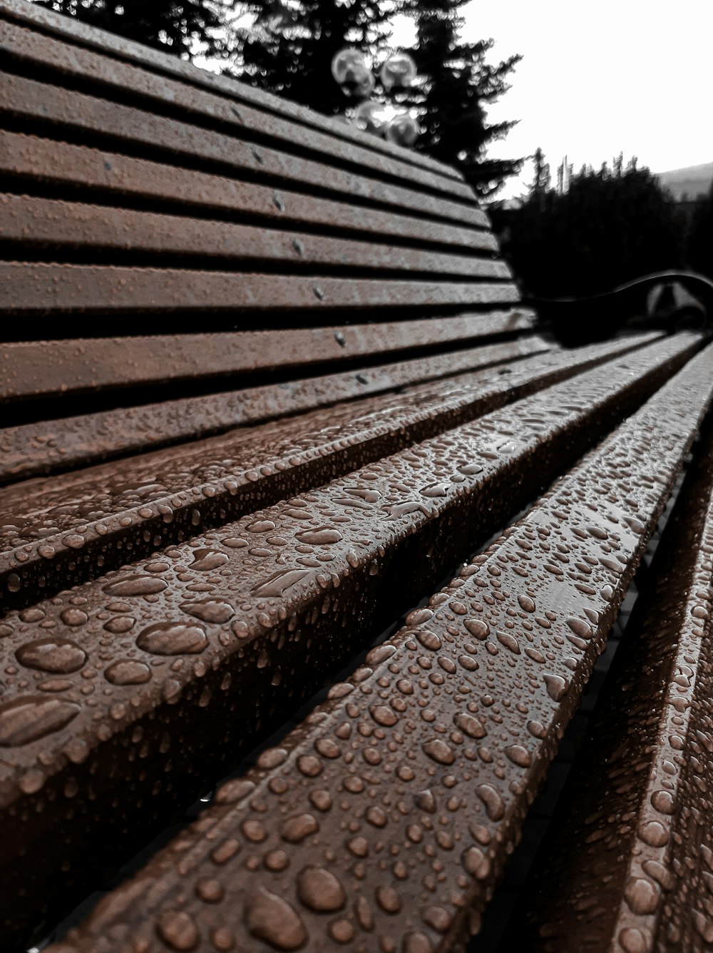 a close up of a wooden bench with water droplets on it