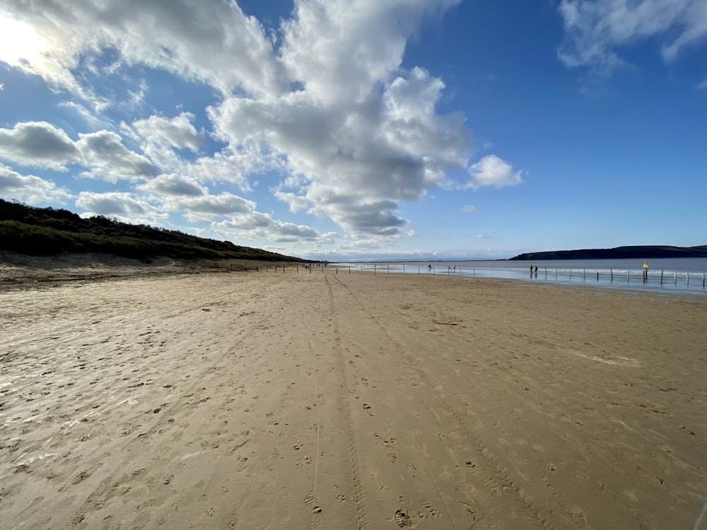 a sandy beach under a blue sky with clouds