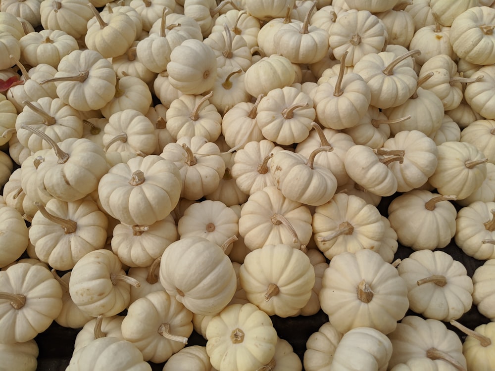 a pile of white pumpkins sitting on top of a table