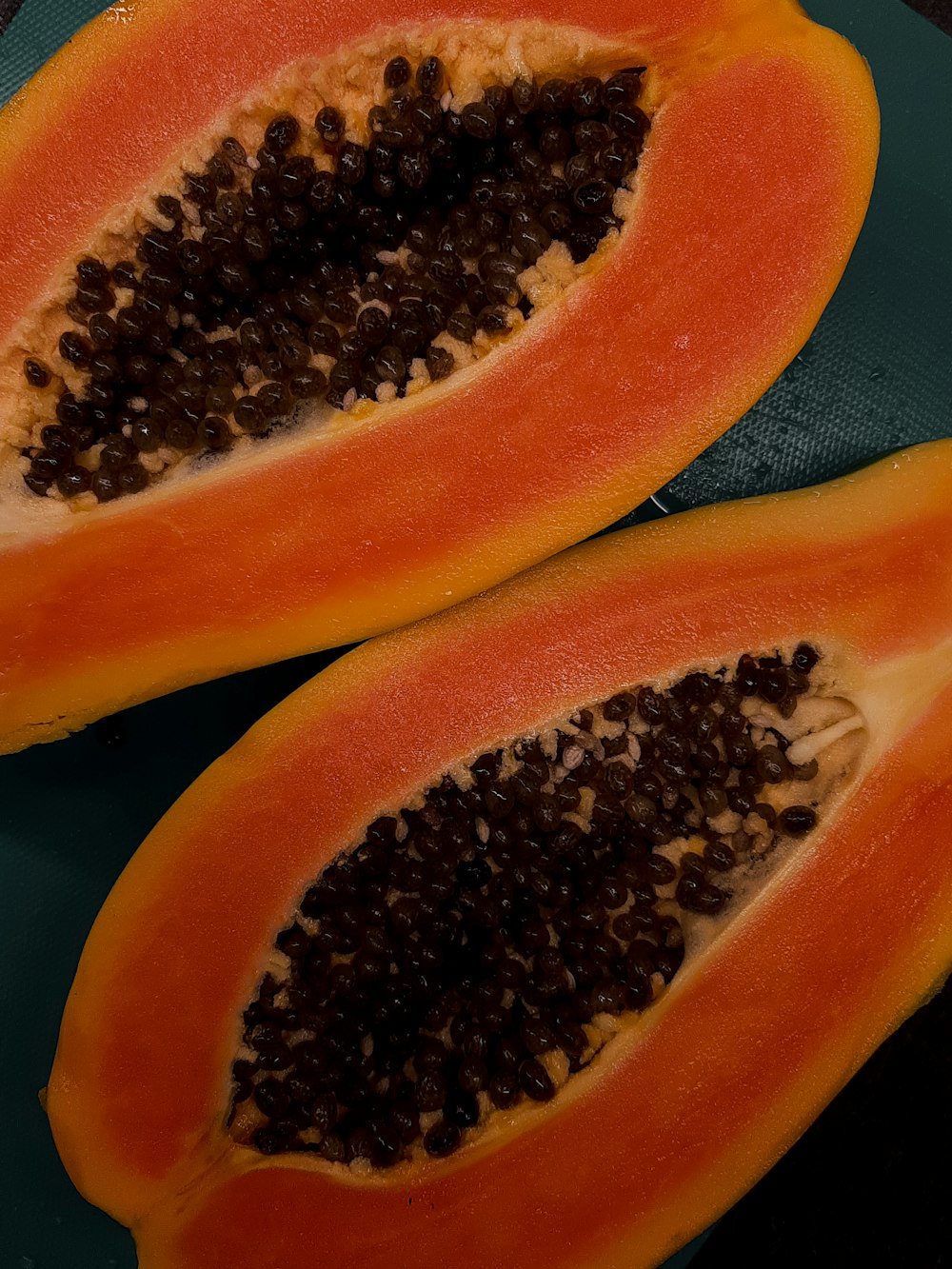 a papaya cut in half on a cutting board
