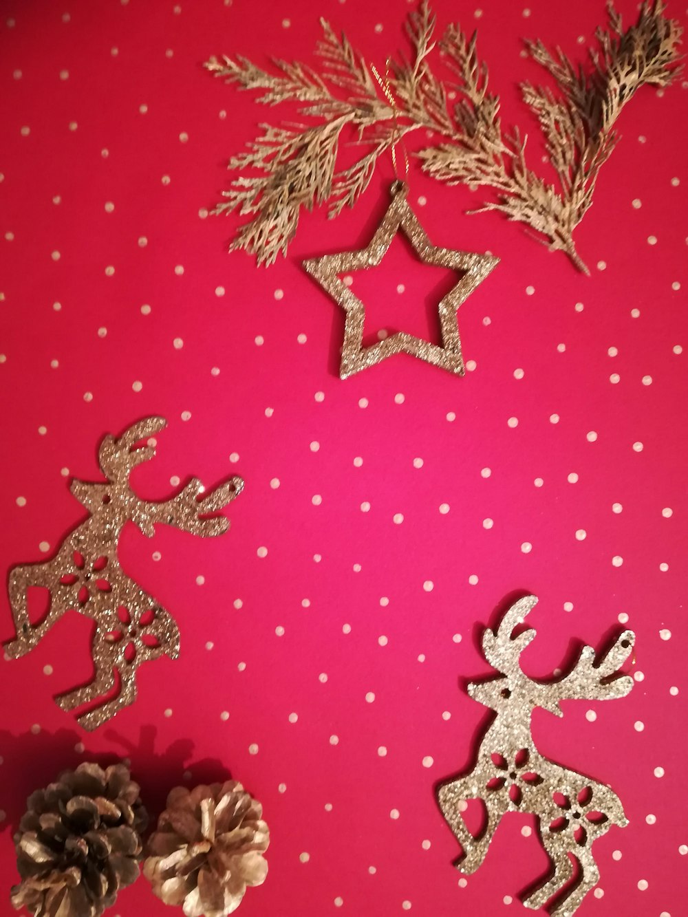 a red table topped with christmas decorations and pine cones