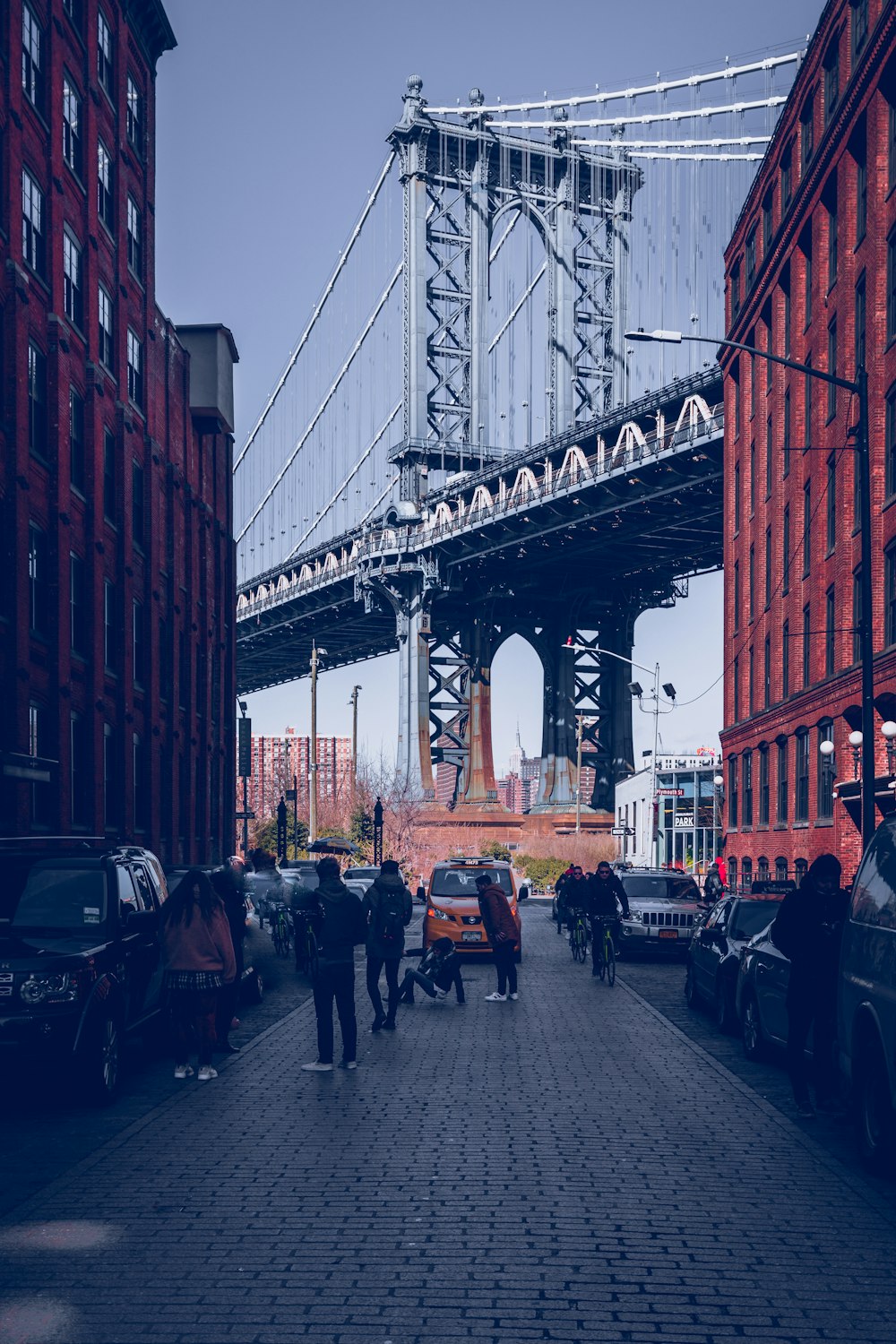 um grupo de pessoas andando por uma rua sob uma ponte
