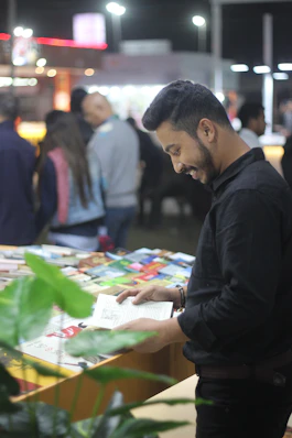 a man standing at a table looking at a book
