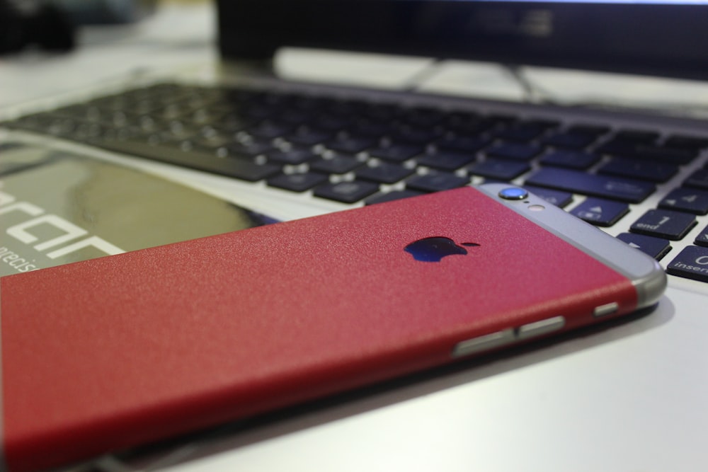 a red iphone sitting next to a laptop computer