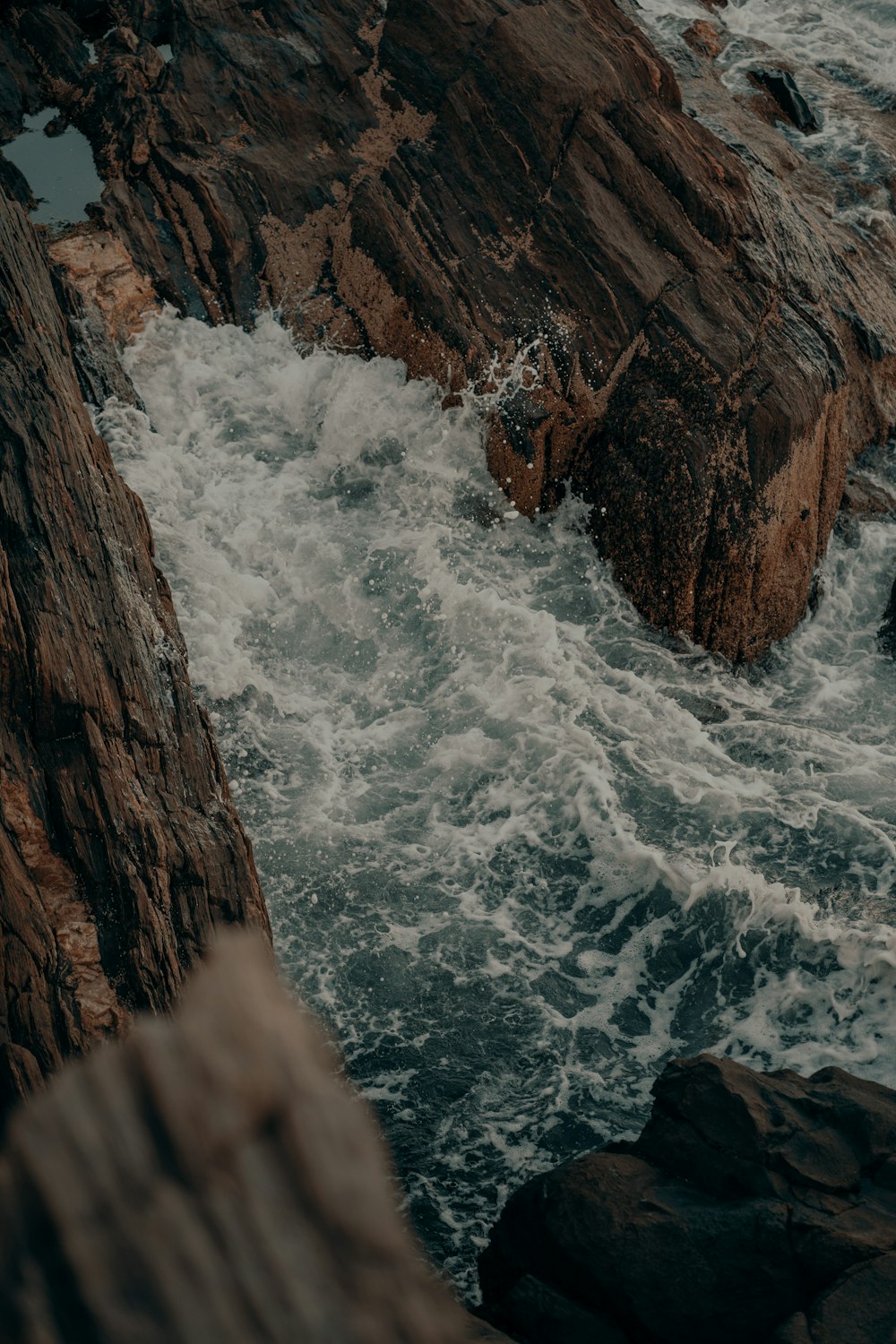 a person standing on a rock next to a body of water