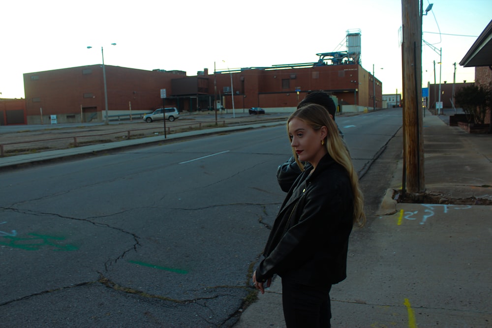 a woman standing on the side of a road