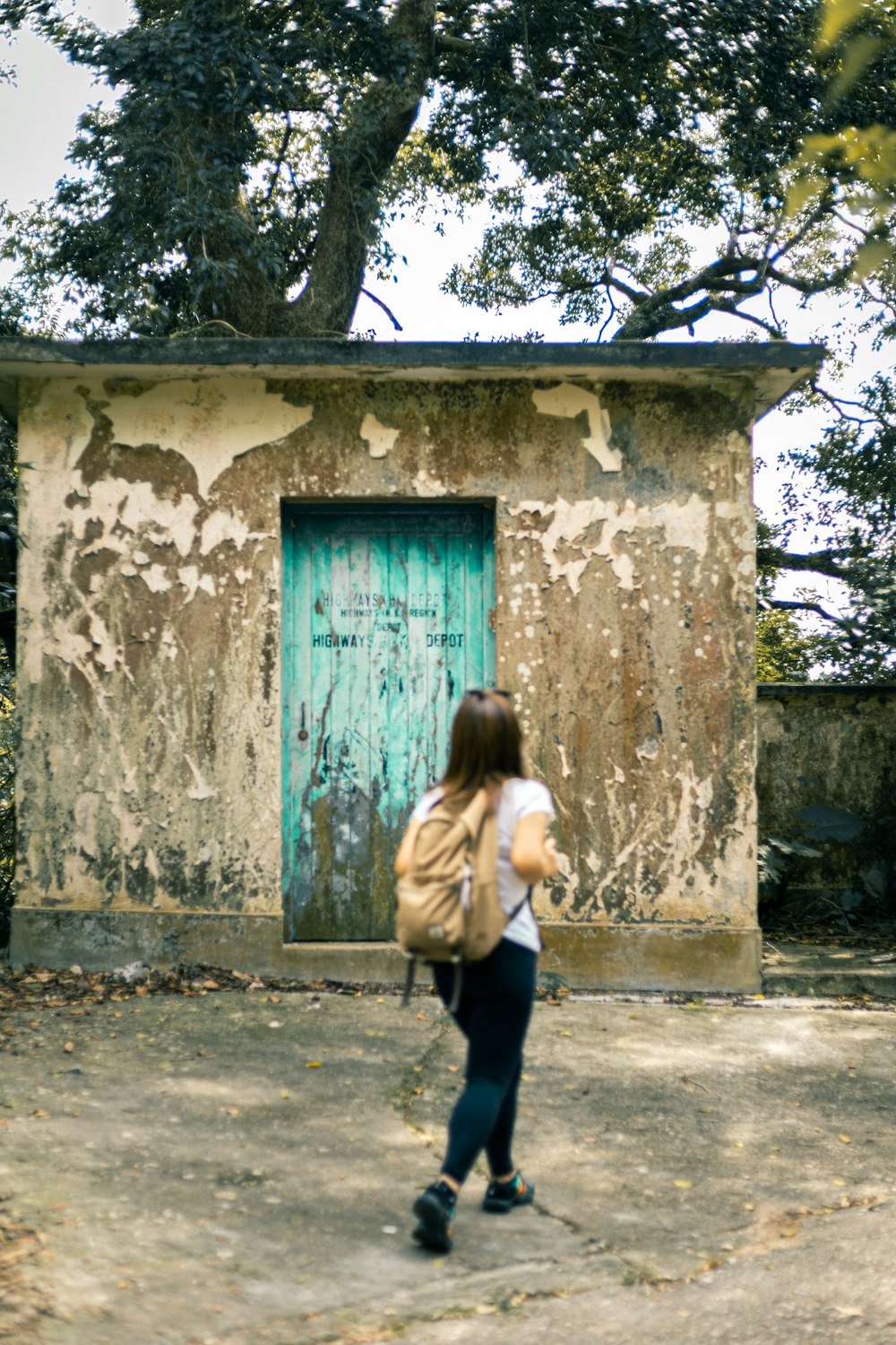 a woman with a backpack walking past a building