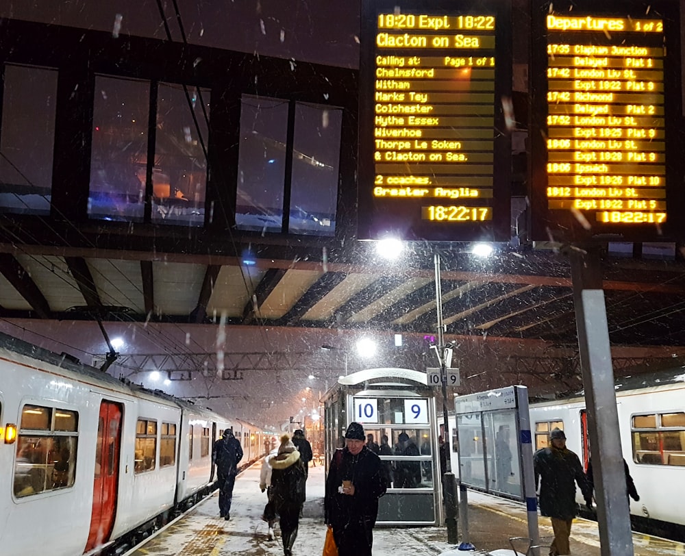 a group of people standing next to a train at a train station