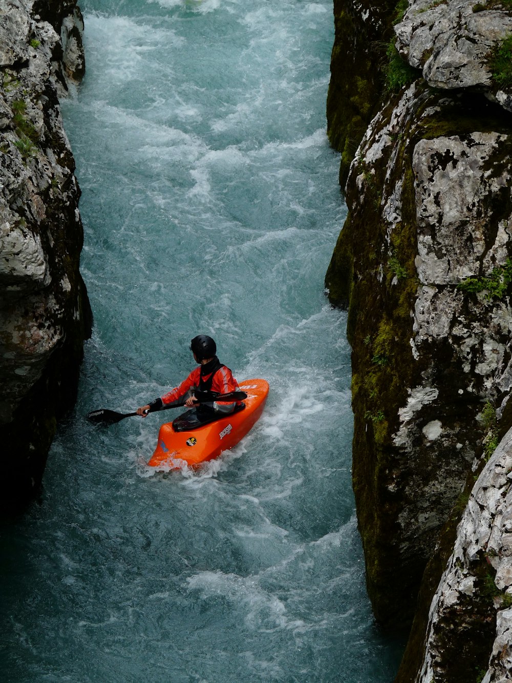 a person in an orange kayak in a river
