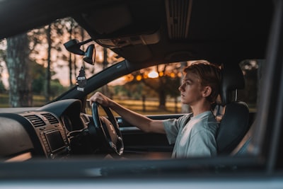 a man sitting in a car with his hand on the steering wheel