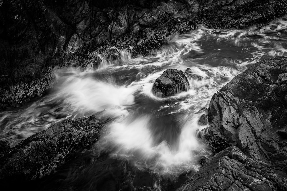 a black and white photo of waves crashing on rocks