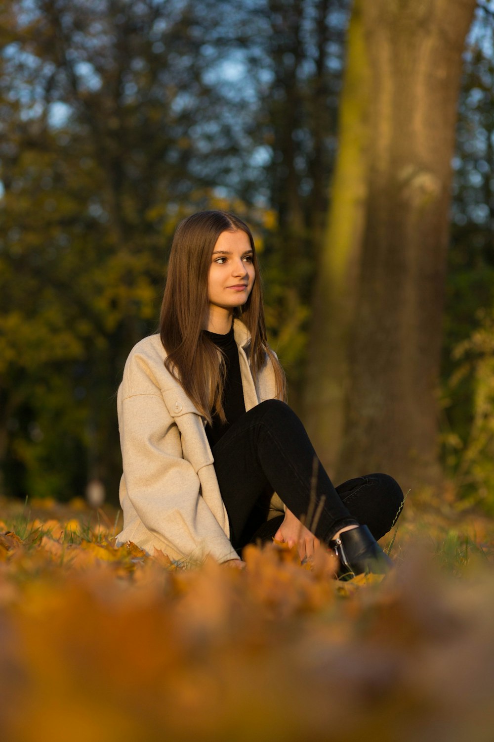 a woman sitting on the ground in front of a tree