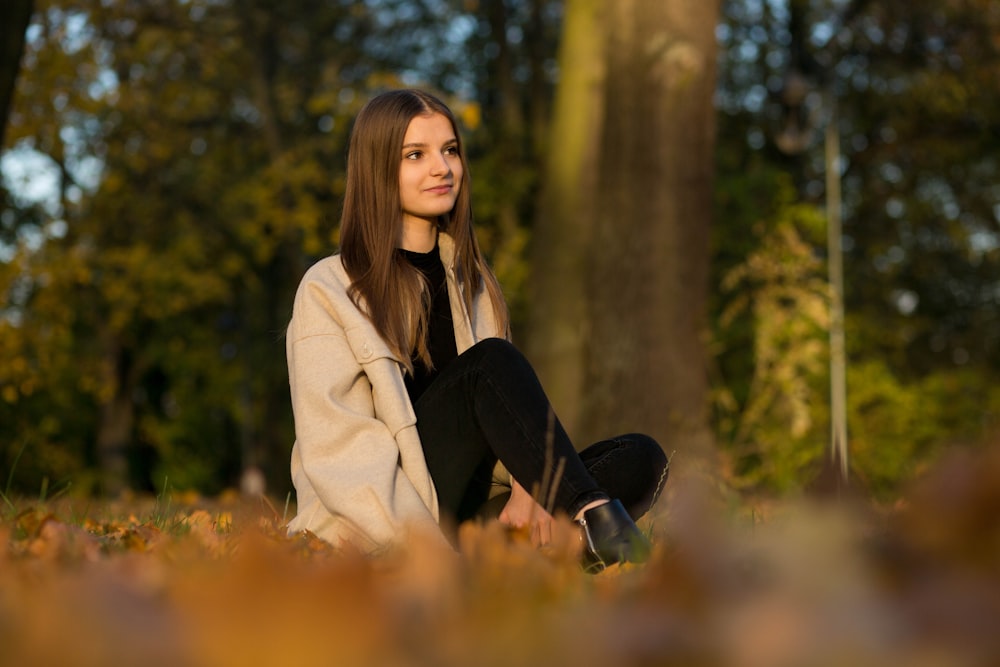 a woman sitting on the ground in a forest