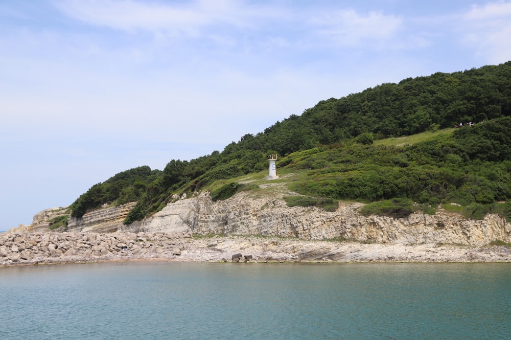 um farol em um penhasco rochoso com vista para um corpo de água