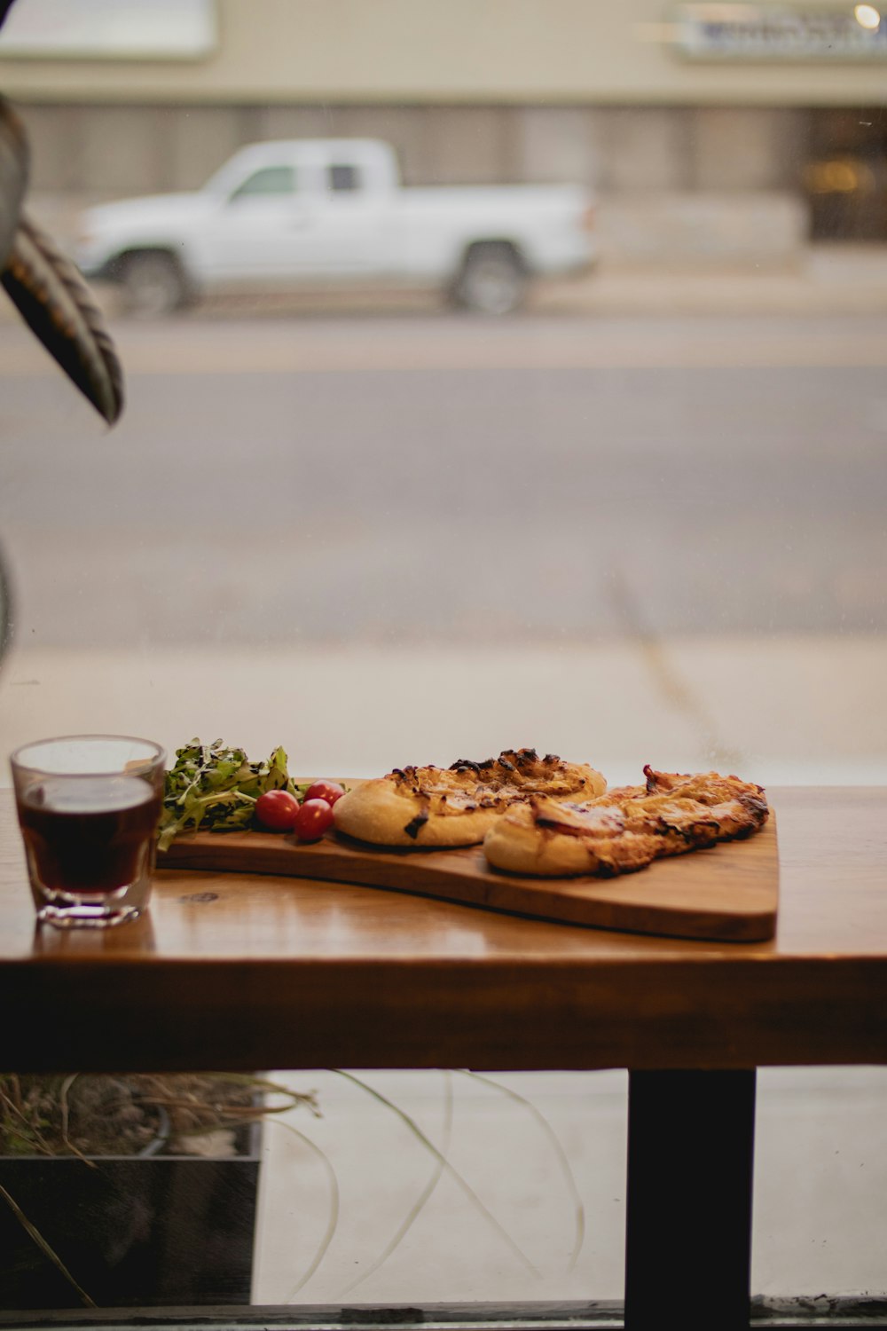 a wooden table with a pizza and a drink on it