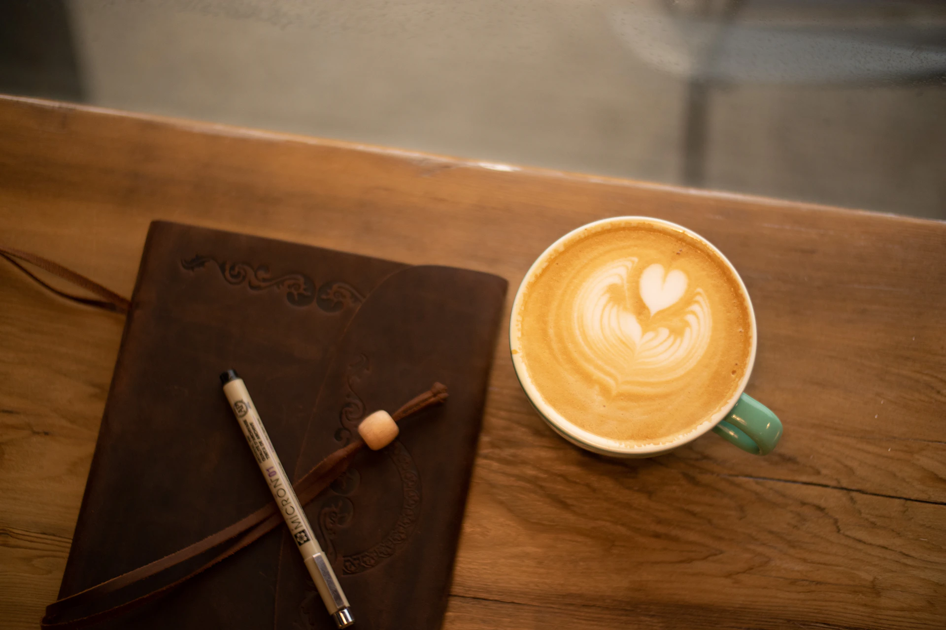 a cup of coffee and a pen on a table