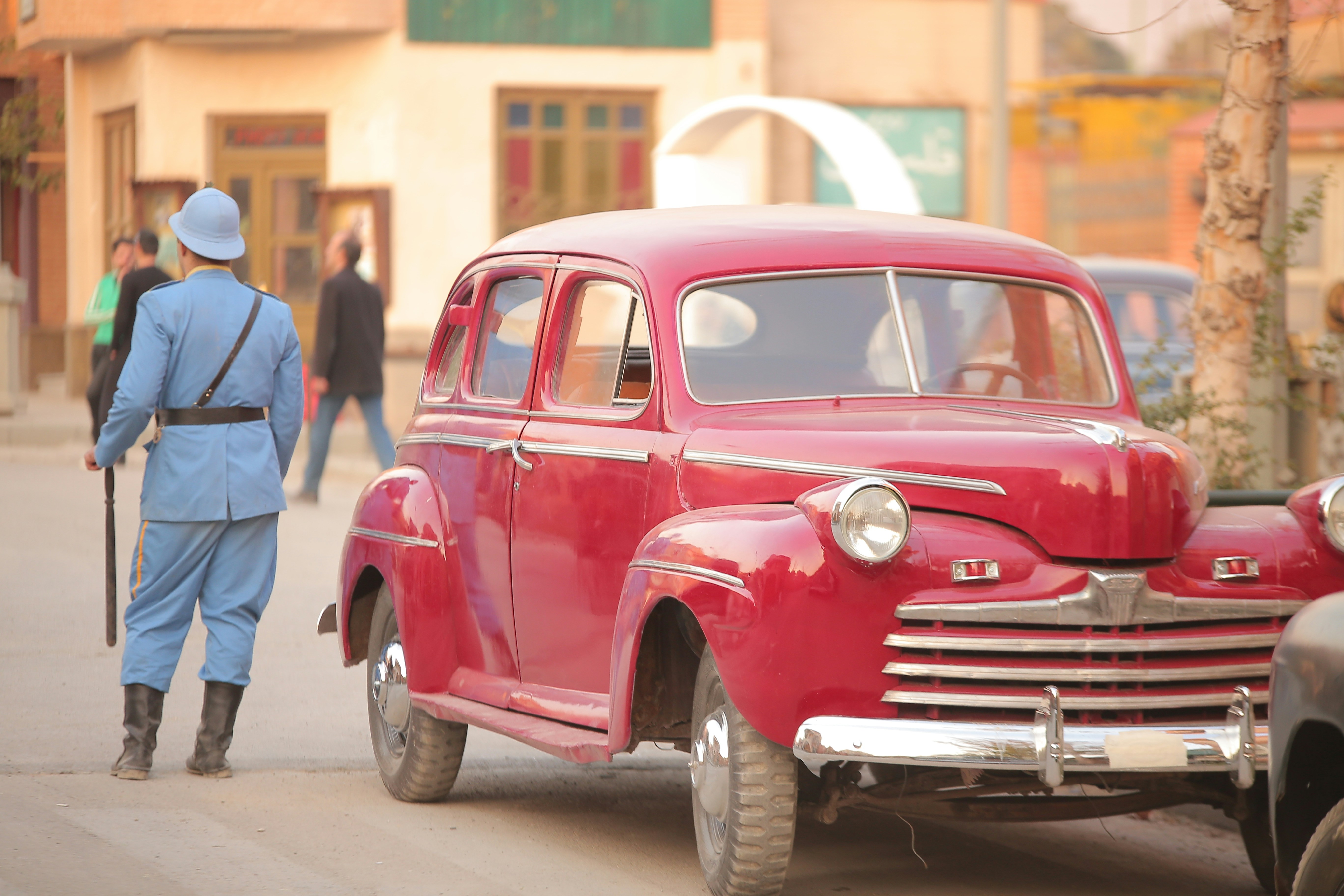 an old red car parked on the side of the road