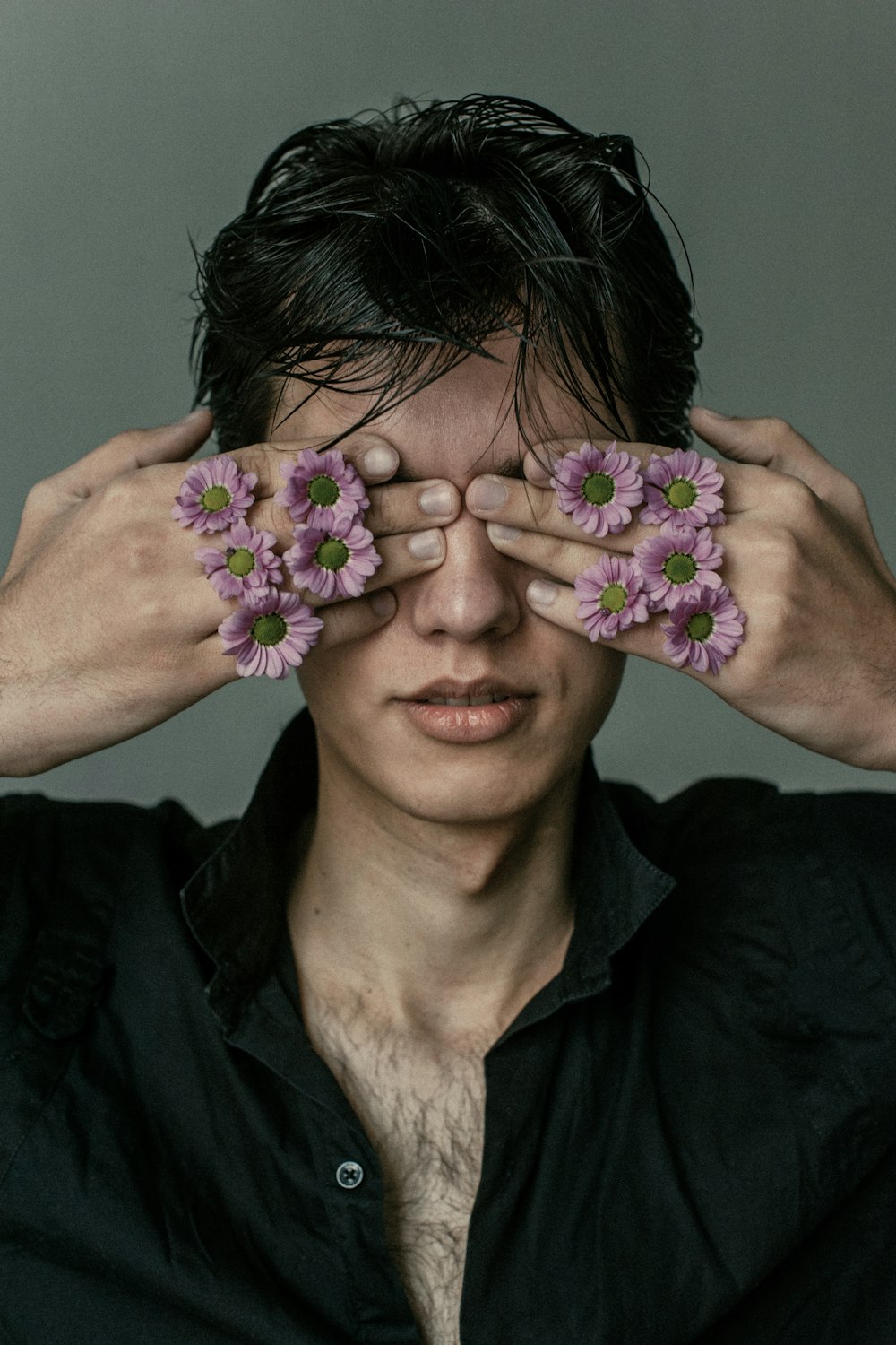 a man covering his eyes with pink flowers