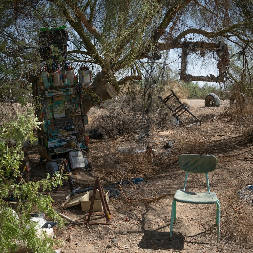 a green chair sitting under a tree in the middle of a field