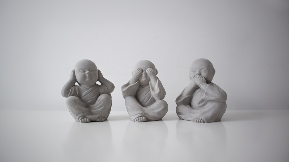 três pequenas estátuas de budas sentadas em uma fileira