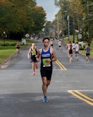A group of participants encouraging each other mid-race along a tree-lined street.
