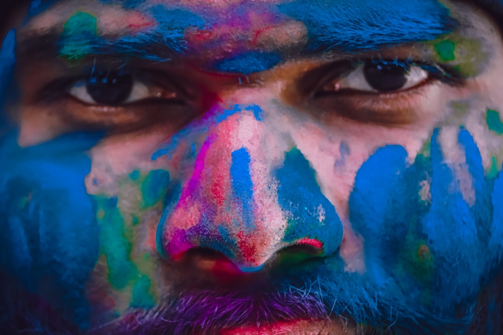a man with blue and pink paint all over his face