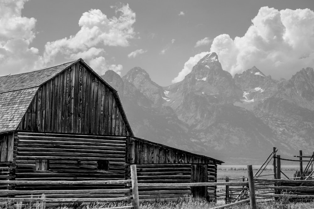 a black and white photo of a barn and mountains