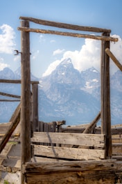 Workers framing a sturdy cabin structure with rugged mountain views in the background.