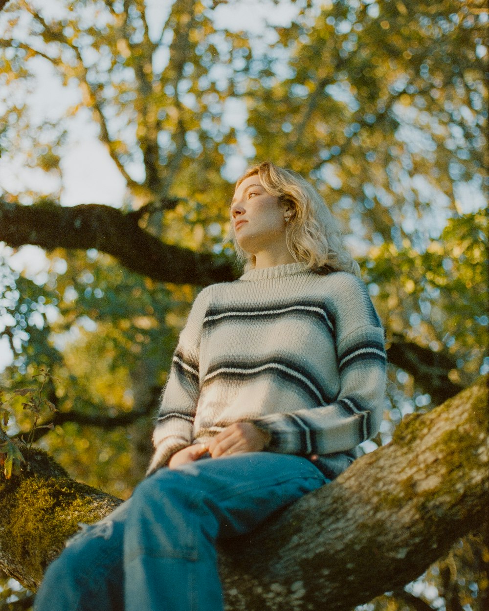 a woman sitting on a tree branch looking up