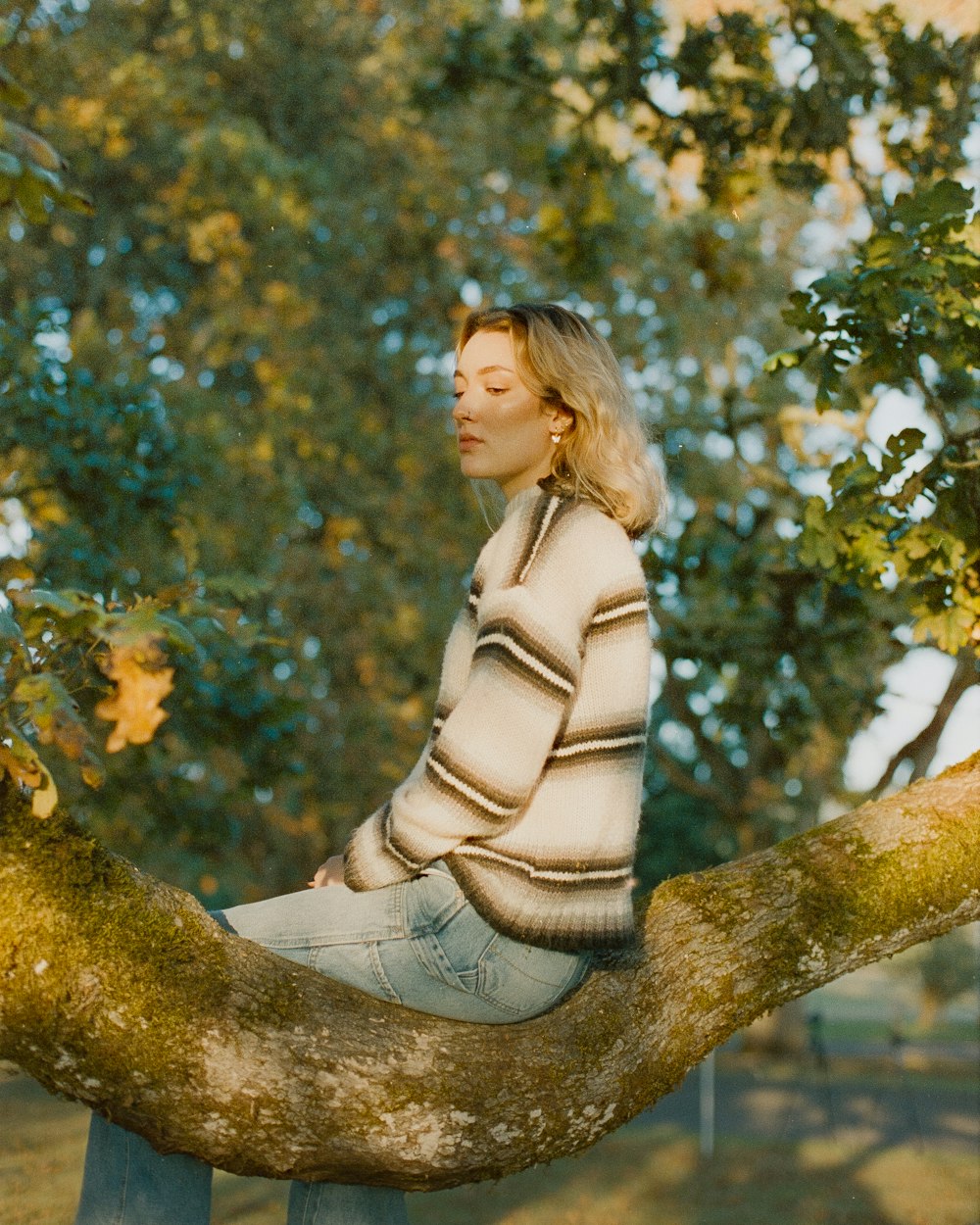 a woman sitting on a tree branch with her eyes closed