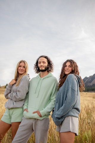 three people standing in a field of tall grass