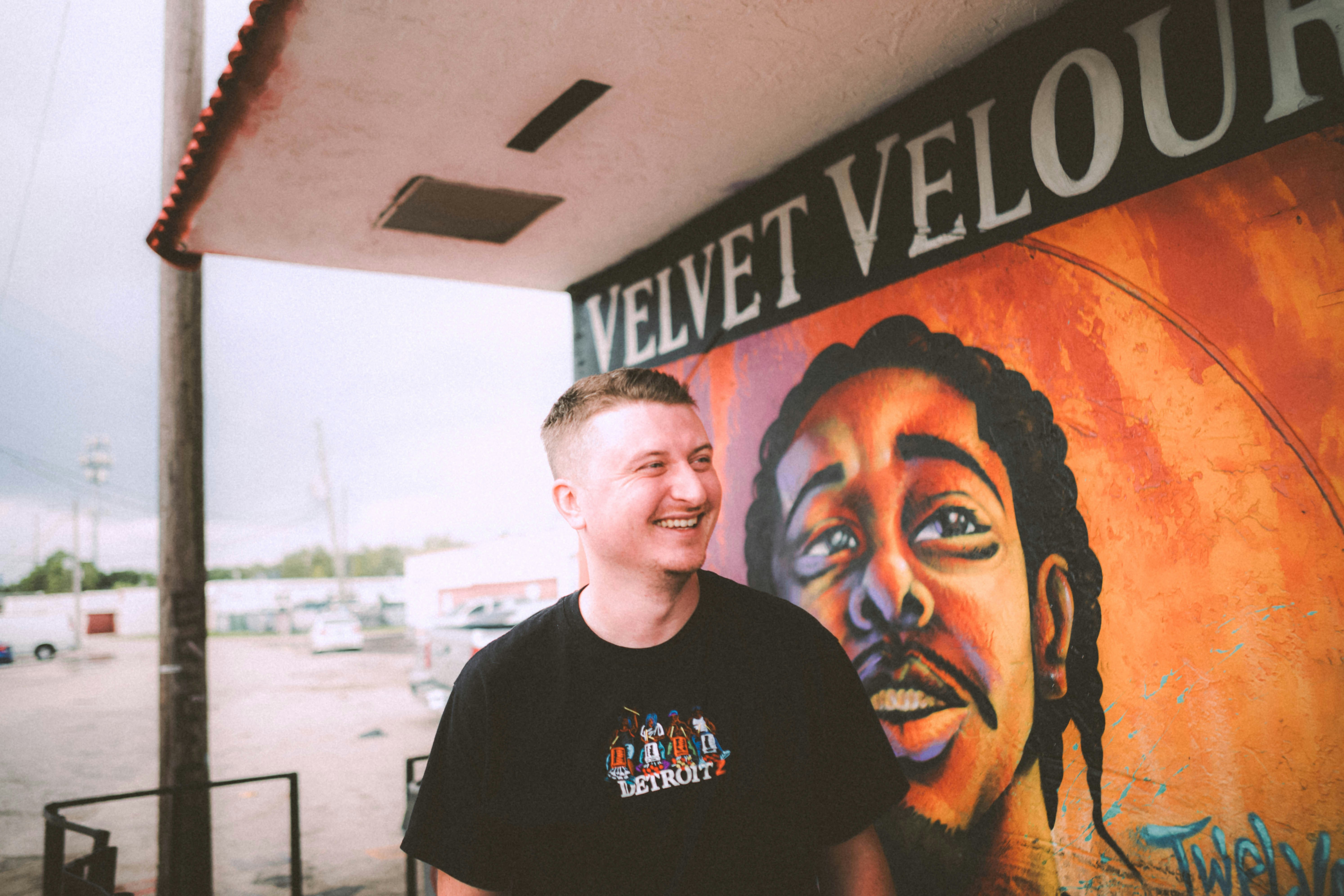 a man standing in front of a wall with a painting on it